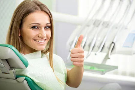 woman in dental chair giving thumbs up